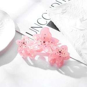 Détail de la pince à cheveux fleur en résine rose avec strass colorés et fini nacré