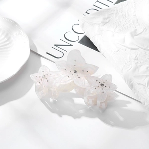 Détail d'une pince à cheveux florale en acétate blanc crème avec strass brillants