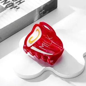 Close-up of red milk carton hair claw clip with white milk lettering on white cloud stand
