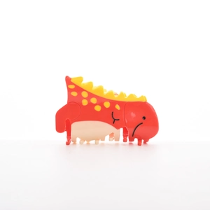 Détail de la pince à cheveux dinosaure rouge avec pois jaunes et prise solide