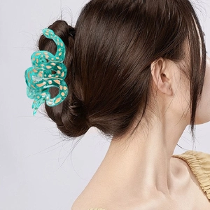Pince à cheveux serpent en acétate vert avec taches dorées sur un chignon élégant