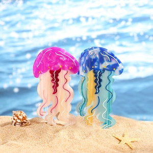 Dettaglio macro di mollette per capelli a medusa in acetato rosa e blu sulla sabbia