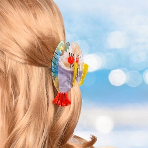 Detail of red clownfish hair claw clip made of acetate on wavy golden hair