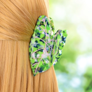 Leaf-shaped acetate hair claw with marble texture shown clipped on long hair
