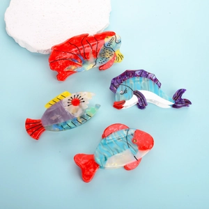Detailed close-up of colorful fish-shaped acetate hair claws on a blue background