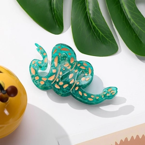 Vue détaillée de la pince à cheveux serpent en forme de S verte avec taches oranges