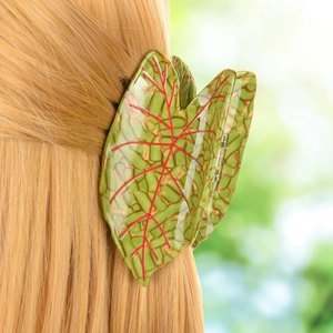 Detail of leaf-shaped hair claw clip with red veins on golden blonde hair