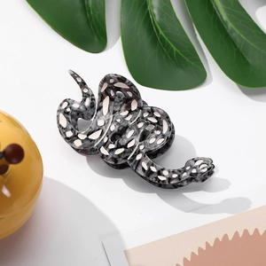 Détail du clip à cheveux serpent en acétate avec texture marbrée et points roses fins