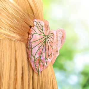 Close-up of a pink leaf-shaped acetate hair claw clip with pearlescent finish on blonde hair