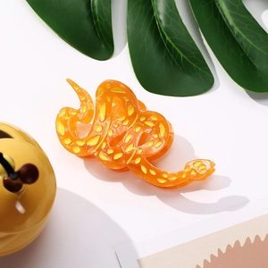 Vue détaillée d'une pince à cheveux serpent orange avec des taches jaunes sur blanc