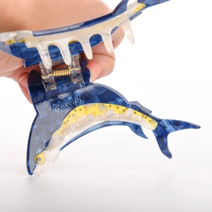 Dettaglio della molletta per capelli a delfino in acetato blu marmo con molla dorata