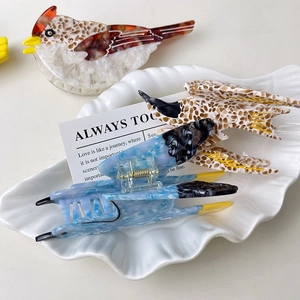 Three colorful bird-shaped acetate hair claws in a seashell plate, elegant bird hair clips
