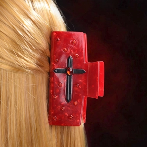 Détail de la pince à cheveux rouge marbrée avec croix en strass sur cheveux blonds