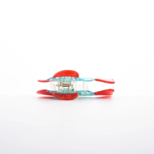 Macro detail of tropical fish hair claw with red and blue marble pattern and metal spring