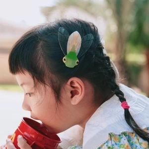 Barrette cigale avec corps vert et ailes translucides portée par un mannequin