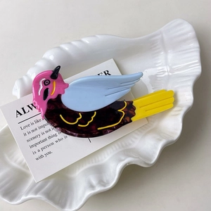 Detail view of bird-shaped acetate hair claw with colorful pink and blue sections