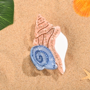 Vue détaillée d'une pince à cheveux coquillage avec strass brillants sur le sable