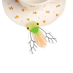 Barrette à cheveux cigale en acétate avec ailes translucides sur une soucoupe fleurie