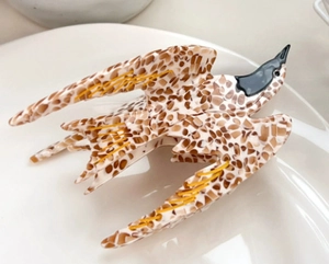 Detailed close-up of a large parrot-shaped acetate hair claw clip with tortoise patterns