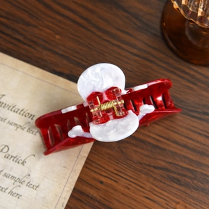 Macro detail of red and white marble acetate hair claw clip with golden metal spring