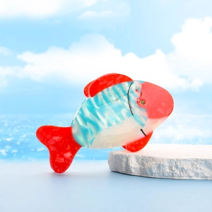 Tropical fish hair claw clip in red and blue marbled acetate on a beach background