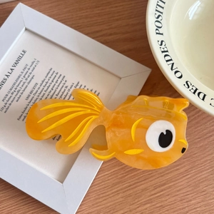 Detail view of goldfish acetate hair claw clip with orange marble pattern and creative design