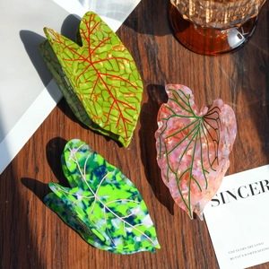 Detail of three acetate leaf hair claws with marble textures on a wooden background