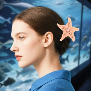 Détail d'une pince à cheveux étoile de mer rose avec strass portée par un mannequin en mer