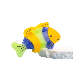 Tropical fish hair claw clip in yellow and blue acetate material on a white stone base