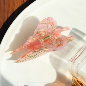 Detail of pink acetate butterfly hair claw with pearlescent texture and gold metal spring