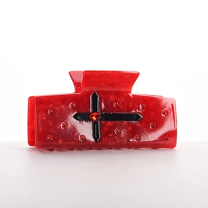 Gros plan d'une pince à cheveux rouge marbrée avec un design de croix gothique