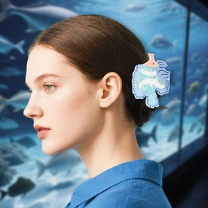 Détail d'une pince à cheveux en acétate bleu avec strass portée sur fond de scène marine