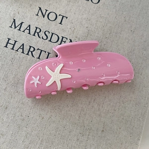 Detalle de pinza para pelo rosa de acetato con motivos de estrellas de mar y strass brillantes