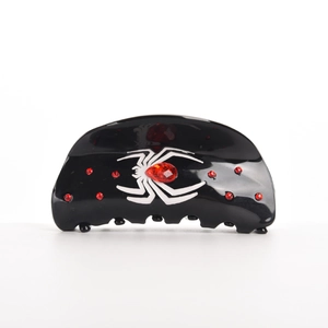 Détail d'une pince à cheveux noire en acétate avec araignée et strass rouge