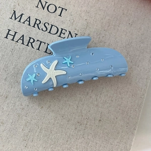 Detalle de la pinza para el pelo de acetato azul claro con estrellas de mar y strass
