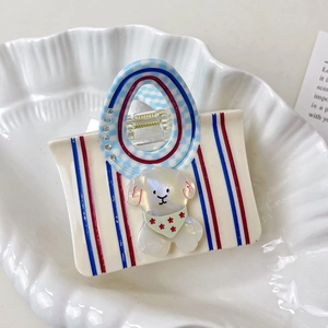 Détail d'une pince à cheveux créative en acétate en forme de sac avec un décor de chiot