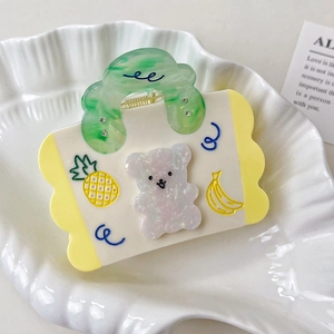Détail de la pince à cheveux en forme de sac avec ours pailleté et décors de fruits