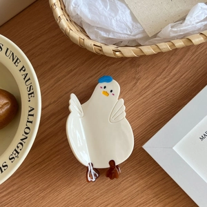 Pince à cheveux canard mignon en acétate brillant posée sur une table en bois rustique