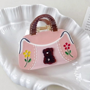 Vue détaillée de la pince à cheveux en forme de sac à ours rose avec fleurs et strass