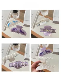Detailed views of pearl white and iridescent purple starfish hair claws with whale patterns