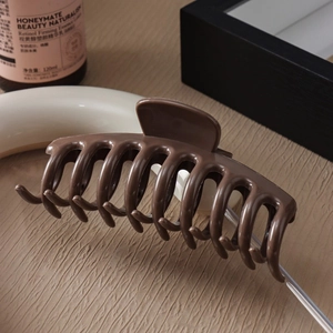 Detail of a large chocolate brown silicone shark hair claw clip with rounded teeth design