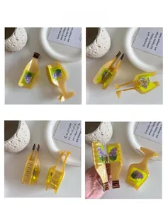 Detail of yellow acetate hair clips in wine bottle and goblet shapes with grape motifs