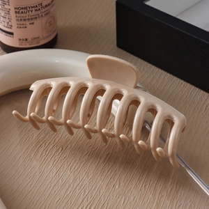 Detail view of large beige silicone shark hair claw clip on a wooden surface texture