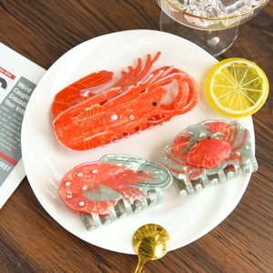 Détail de pinces à cheveux en acétate sur le thème marin, formes homard et crabe avec strass