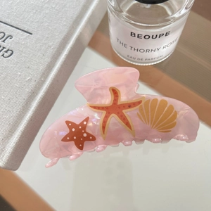 Close-up of pink acetic acid hair claw clip with colorful starfish and seashell patterns