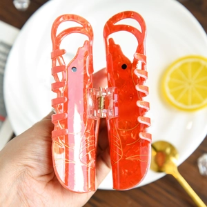 Vue détaillée de la pince à cheveux homard orange avec texture marbrée et accents dorés