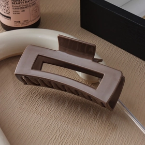 Detailed view of deep brown rectangular hair claw clip with non-slip teeth texture
