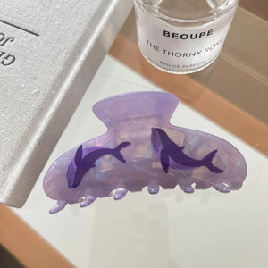 Detail of purple acetate hair claw with whale patterns and iridescent mica texture