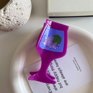 Close-up of a purple wine glass hair claw clip with grape pattern on a white tray