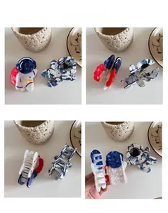 Detail view of astronaut-shaped acetate hair claw clips in white and marble blue finishes